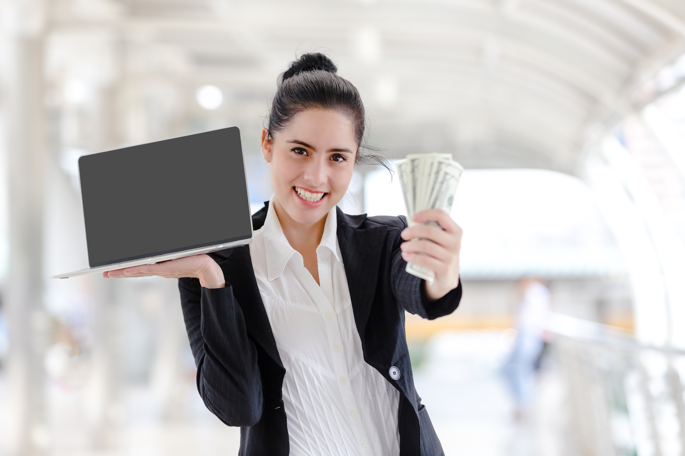 Woman standing holding working with a laptop and money ,Make money online ,Financial concept